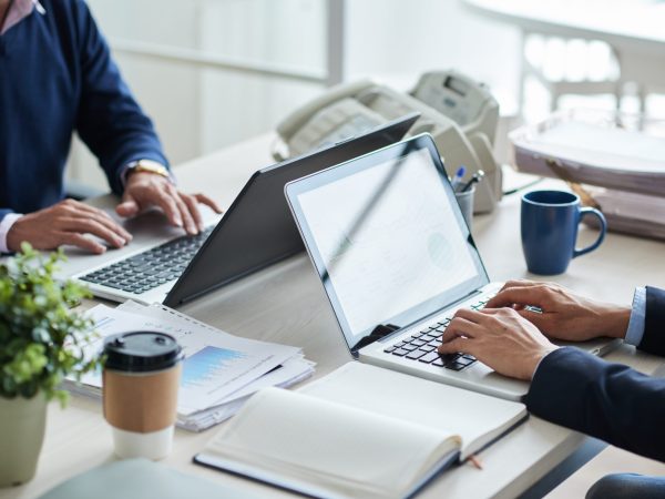 Cropped image of business people working on laptops in office